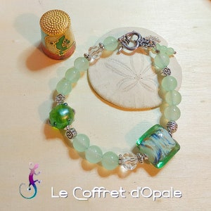 Peut inclure: Un bracelet en jade vert avec des perles argentées et un charme en verre vert. Le bracelet a un fermoir argenté et est fait de pierres naturelles.