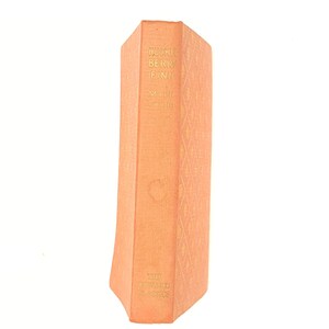 May include: An orange book with the title "Huckleberry Finn" by Mark Twain. The book is part of "The Reward Classics" series.