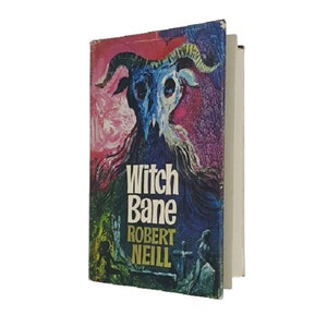 Peut inclure: Une couverture de livre de poche vintage avec une illustration colorée d'une chèvre à tête de crâne et des cornes. Le titre "Witch Bane" est écrit en lettres blanches en gras avec le nom de l'auteur "Robert Neill" en dessous.