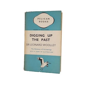 May include: A blue book cover with the title "Digging Up The Past" by Sir Leonard Woolley. The book is part of the Pelican Books series and features a black and white illustration of a bird in flight.