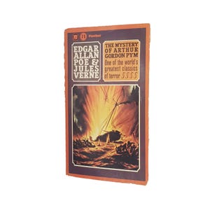 Puede incluir: Una portada de libro de bolsillo vintage con fondo naranja. El título es "El misterio de Arthur Gordon Pym" de Edgar Allan Poe y Jules Verne. La portada presenta una ilustración de un barco envuelto en llamas.