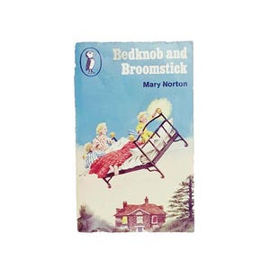 May include: Vintage book cover for "Bedknob and Broomstick" by Mary Norton. The cover features an illustration of children on a flying bed over a house. The book cover is blue with the title and author's name.