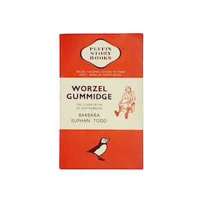 Puede incluir: Una cubierta de libro roja con el título "Worzel Gummidge" y el subtítulo "The Scarecrow of Scatterbrook" de Barbara Euphan Todd. La cubierta presenta una ilustración de dibujos animados de un espantapájaros y un frailecillo.