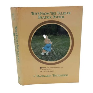 May include: A yellow book cover with the title "Toys From The Tales of Beatrix Potter" and a picture of Peter Rabbit from the book "The Tale of Peter Rabbit". The book is by Margaret Hutchings.