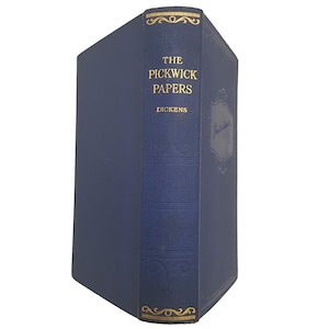Może przedstawiać: Niebieska książka w twardej oprawie ze złotymi napisami na grzbiecie. Tytuł to "The Pickwick Papers" autorstwa Dickensa.