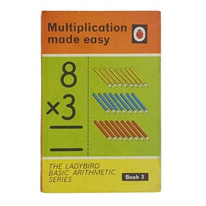 Könnte beinhalten: Ein Vintage-Ladybird-Buch mit dem Titel "Multiplication made easy" mit einem roten Marienkäfer-Logo. Das Buch zeigt eine visuelle Darstellung des Multiplikationsproblems 8 x 3, wobei farbige Bleistifte die Gleichung veranschaulichen.