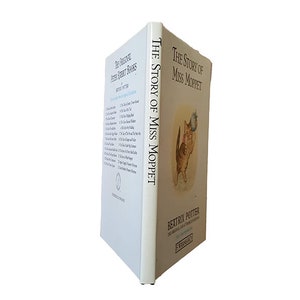 May include: The Story of Miss Moppet by Beatrix Potter. A white book with a blue and white illustration of a cat holding a bird on the cover.