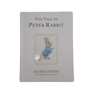 Può includere: Una copertina di libro bianca con il titolo "The Tale of Peter Rabbit" in testo nero. La copertina presenta un'illustrazione di Peter Rabbit che indossa una giacca blu e corre. L'autore, Beatrix Potter, è stampato sotto l'illustrazione con il testo "The original and authorized edition".