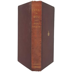 Może przedstawiać: Brązowa książka w skórzanej oprawie z pozłacanymi napisami na grzbiecie. Tytuł to "Sketches by Boz", a autorem jest "Charles Dickens".