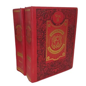 Puede incluir: Dos libros de tapa dura rojos, "Vol I" y "Vol II", de "The Illustrated Library" de Charles Dickens. Las portadas presentan letras doradas y diseños florales ornamentados. Los libros están sobre un fondo blanco.