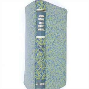 May include: A blue and green book with a gold spine. The spine reads "35MM SINGLE LENS REFLEX MANUAL" and "BATTER G.B. 771.314".