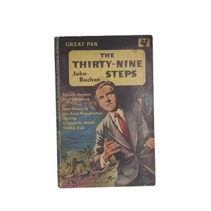 May include: A vintage paperback book cover featuring a man in a suit and tie. The title of the book is "The Thirty-Nine Steps" by John Buchan. The cover also includes the text "Richard Hannay's First Adventure" and "Now Filmed by the Rank Organisation starring Kenneth More and Taina Elg".