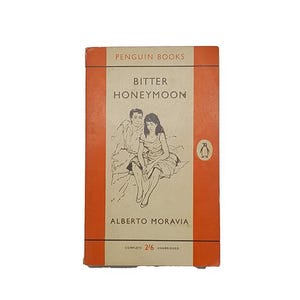 Peut inclure: Livre de poche vintage intitulé "Bitter Honeymoon" d'Alberto Moravia, publié par Penguin Books. La couverture présente une illustration d'un couple et le logo Penguin. Le livre a un code couleur rouge et crème.