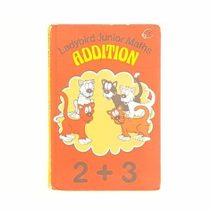 Könnte beinhalten: Ein rotes Buch mit dem Titel "Ladybird Junior Maths Addition" und einem Bild von vier Katzen. Das Buch hat die Gleichung "2 + 3" auf dem Einband.
