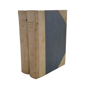 Puede incluir: Conjunto de dos volúmenes de "Tennyson's Poetical Works" con lomo azul y cubiertas de color crema. Los libros están encuadernados en tapa dura y tienen una estética vintage.