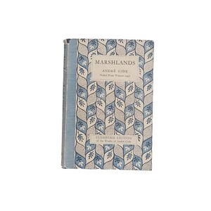 May include: A vintage hardcover book titled "MARSHLANDS" by André Gide, Nobel Prize Winner 1947. The book features a blue spine and a cover with a repeating pattern of blue and white leaf motifs. The text "STANDARD EDITION of the Works of André Gide" is also visible.