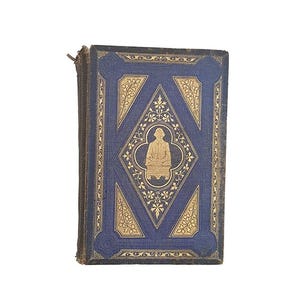 May include: A blue book cover with a gold ornate design. The design features a diamond shape with a person sitting on a throne in the center.