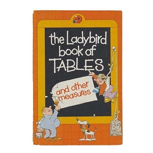 May include: A vintage Ladybird book titled "The Ladybird Book of Tables and other measures". The cover features a cartoon illustration of a man painting a chalkboard with the title of the book. A dog and a ladybug are also depicted on the cover.