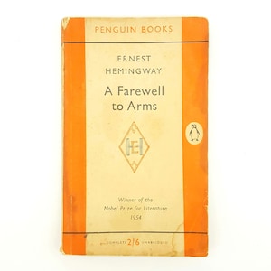 May include: A vintage Penguin Books paperback edition of "A Farewell to Arms" by Ernest Hemingway. The cover is orange with a white Penguin logo and the title in black text. The book is a winner of the Nobel Prize for Literature in 1954.