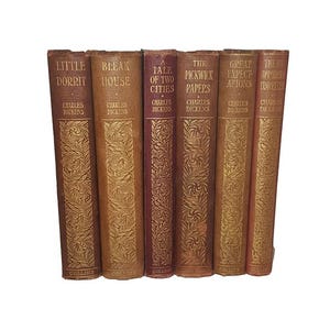 Könnte beinhalten: Ein Satz von acht antiken gebundenen Büchern von Charles Dickens. Die Bücher sind in Braun mit goldenen Lettern und dekorativen Mustern gebunden. Die Titel umfassen "Little Dorrit", "Bleak House", "A Tale of Two Cities", "The Pickwick Papers", "Great Expectations" und "The Uncommercial Traveller".