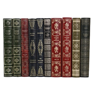 May include: A selection of antique books with leather covers. The spines feature gold lettering, with colours including green, red, and black. Decorative gold patterns are on the covers and spines, creating a classic aesthetic.