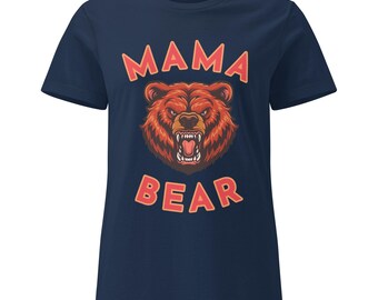 May include: Navy blue t-shirt featuring a red and orange illustration of a bear's head with the text "MAMA BEAR" in red block letters above and below the bear graphic. The bear graphic has an angry expression.
