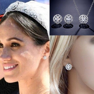 May include: A silver necklace and earrings set with a round, clear crystal center surrounded by smaller crystals. The necklace has a delicate chain.