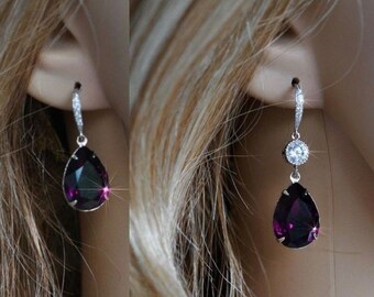 May include: A pair of silver dangle earrings with a teardrop-shaped purple gemstone and a smaller round clear gemstone.