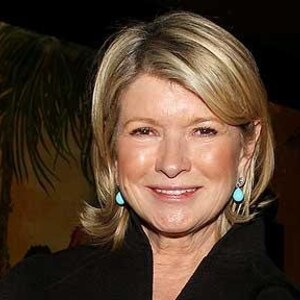 May include: A woman with blonde hair wearing a black blazer and turquoise earrings. She is smiling and looking at the camera.