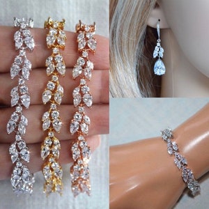 May include: Three delicate bracelets with a leaf design featuring clear cubic zirconia stones. The bracelets are shown in silver, gold, and rose gold.