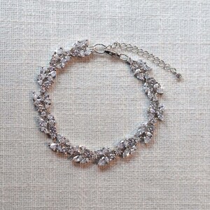 May include: A silver bracelet with a delicate design of leaves and sparkling stones.