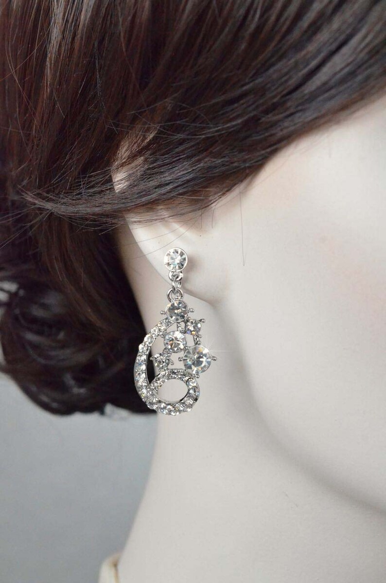 May include: Silver dangle earrings with a cluster of clear rhinestones in a teardrop shape.