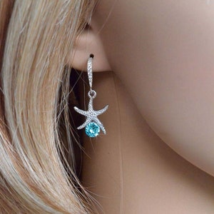 Puede incluir: Pendientes de plata con un cristal azul y un dise&ntilde;o de estrella de mar.