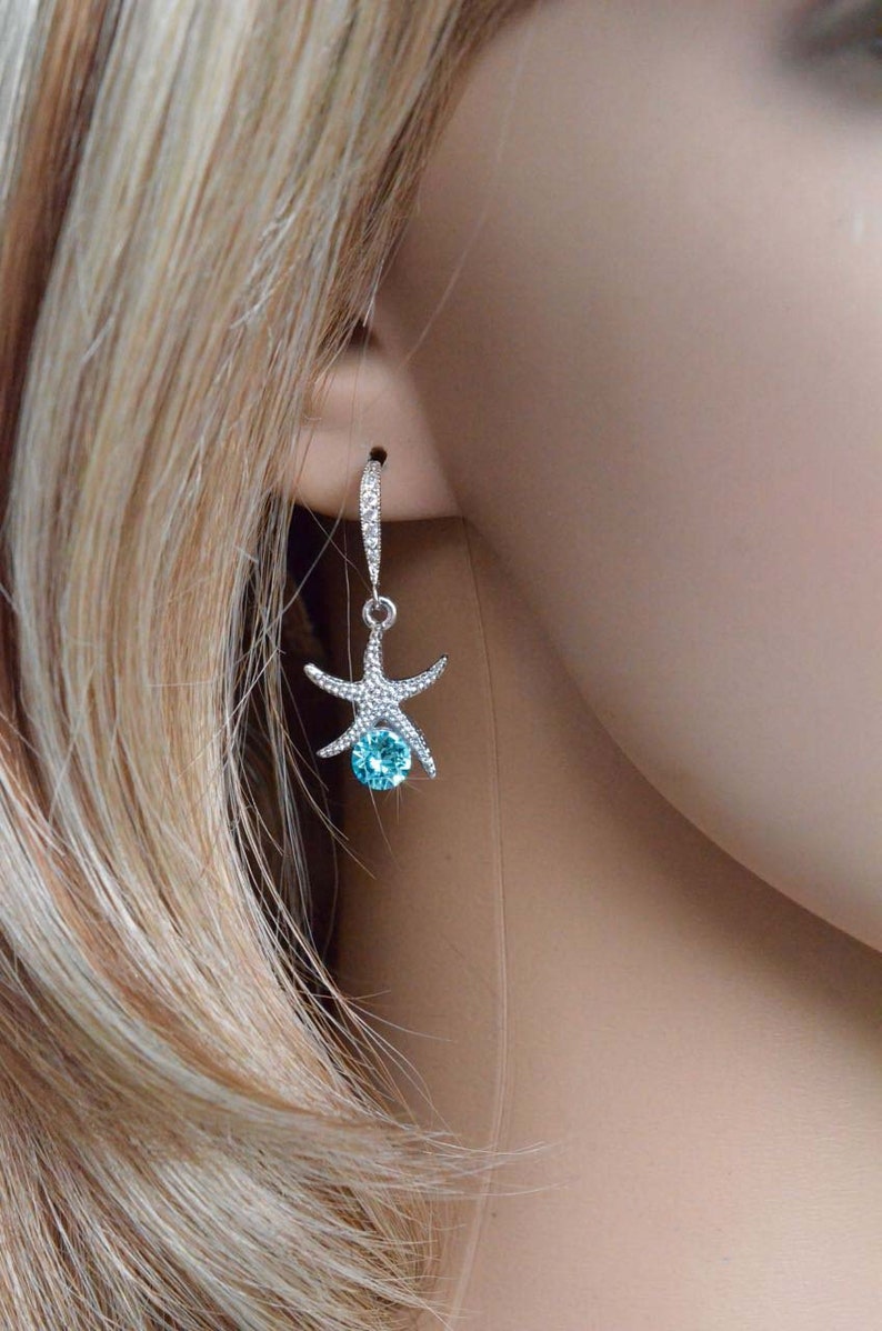 Puede incluir: Pendientes de plata con un cristal azul y un dise&ntilde;o de estrella de mar.