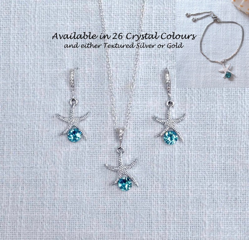 Puede incluir: Un conjunto de joyas de estrella de mar plateadas con acentos de cristal azul. El conjunto incluye un collar, pendientes y una pulsera. Disponible en 26 colores de cristal y en plata texturizada u oro.