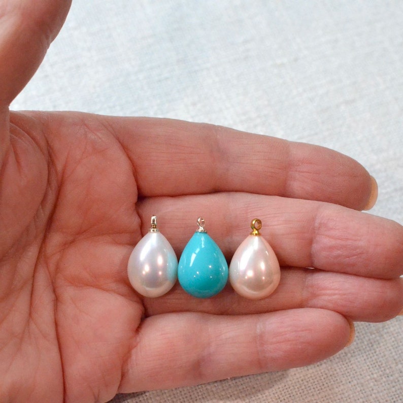 May include: Three teardrop-shaped pendants, one turquoise blue and two white.
