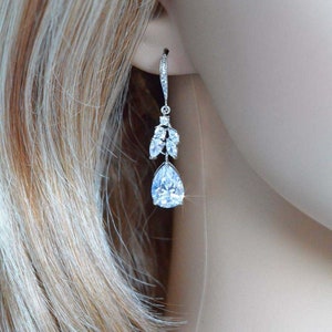 May include: Silver teardrop earrings with a cluster of smaller clear stones above the larger teardrop stone.