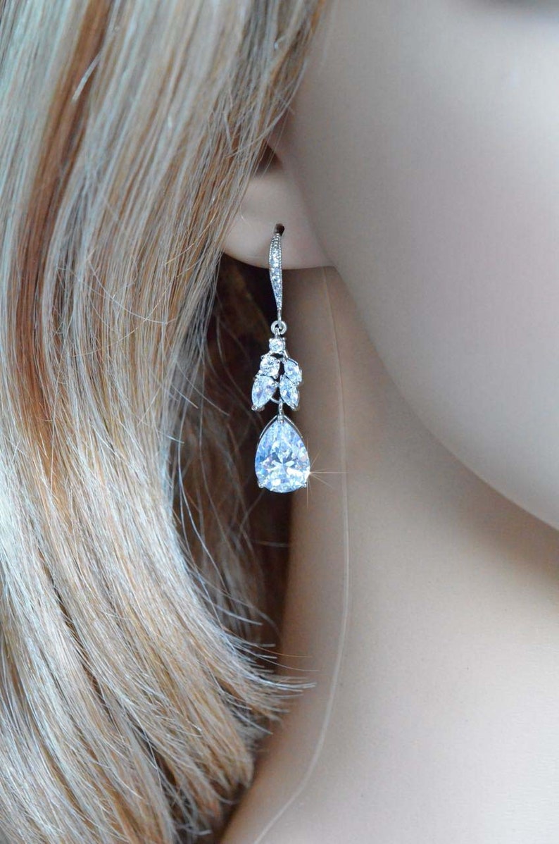 May include: Silver teardrop earrings with a cluster of smaller clear stones above the larger teardrop stone.