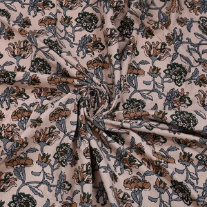 May include: A close-up of a beige fabric with a floral print. The flowers are in shades of brown, green, and blue. The fabric is soft and has a smooth texture.