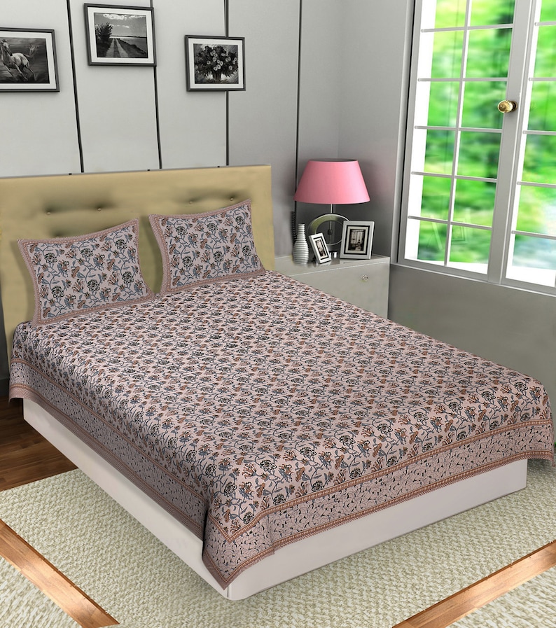 May include: A beige bed with a floral patterned duvet cover and two matching pillowcases. The bed has a white headboard and a beige footboard. The bed is sitting on a light brown rug.
