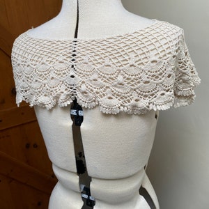 May include: A white crocheted collar with a scalloped edge.