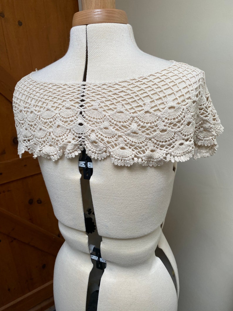 May include: A white crocheted collar with a scalloped edge.