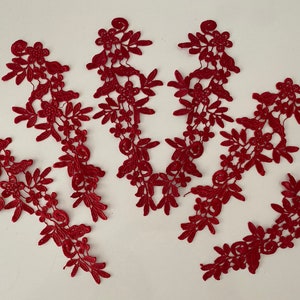 May include: Five red lace appliques with floral designs. The appliques are made of delicate lace and feature intricate floral patterns.
