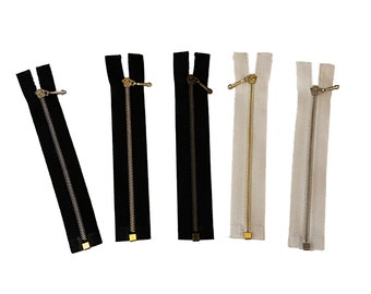 May include: Five different zipper pulls with metal sliders. The zippers are black, black, black, gold, and white.