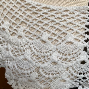 May include: White crochet lace trim with a delicate, intricate pattern. The lace has a soft, fluffy texture and a scalloped edge.