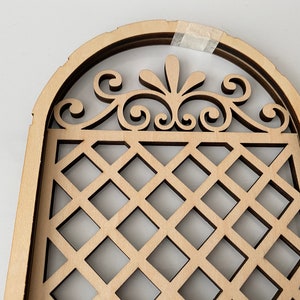 Puede incluir: Un arco de madera con un dise&ntilde;o de celos&iacute;a decorativo y una parte superior con volutas. El arco est&aacute; hecho de m&uacute;ltiples capas de madera, creando un efecto tridimensional.