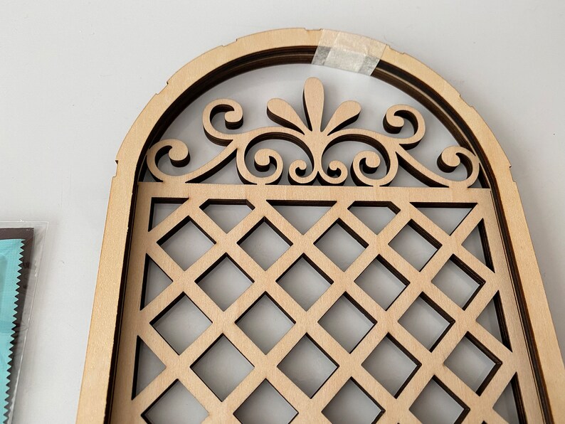 Puede incluir: Un arco de madera con un dise&ntilde;o de celos&iacute;a decorativo y una parte superior con volutas. El arco est&aacute; hecho de m&uacute;ltiples capas de madera, creando un efecto tridimensional.
