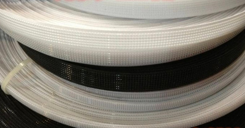 Puede incluir: Primer plano de rollos de cinta de gancho y bucle blanca y negra. La cinta est&aacute; hecha de un material de nylon tejido con peque&ntilde;os agujeros espaciados uniformemente.