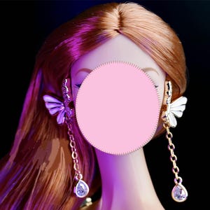 May include: A pair of gold butterfly earrings with clear crystal accents and dangling teardrop crystals.
