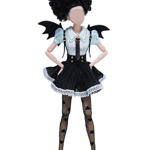 May include: A doll with black curly hair, wearing a black and white dress with a lace trim. The doll has black bat wings, a heart-shaped pendant, and black heart-patterned stockings. The doll is wearing brown shoes.